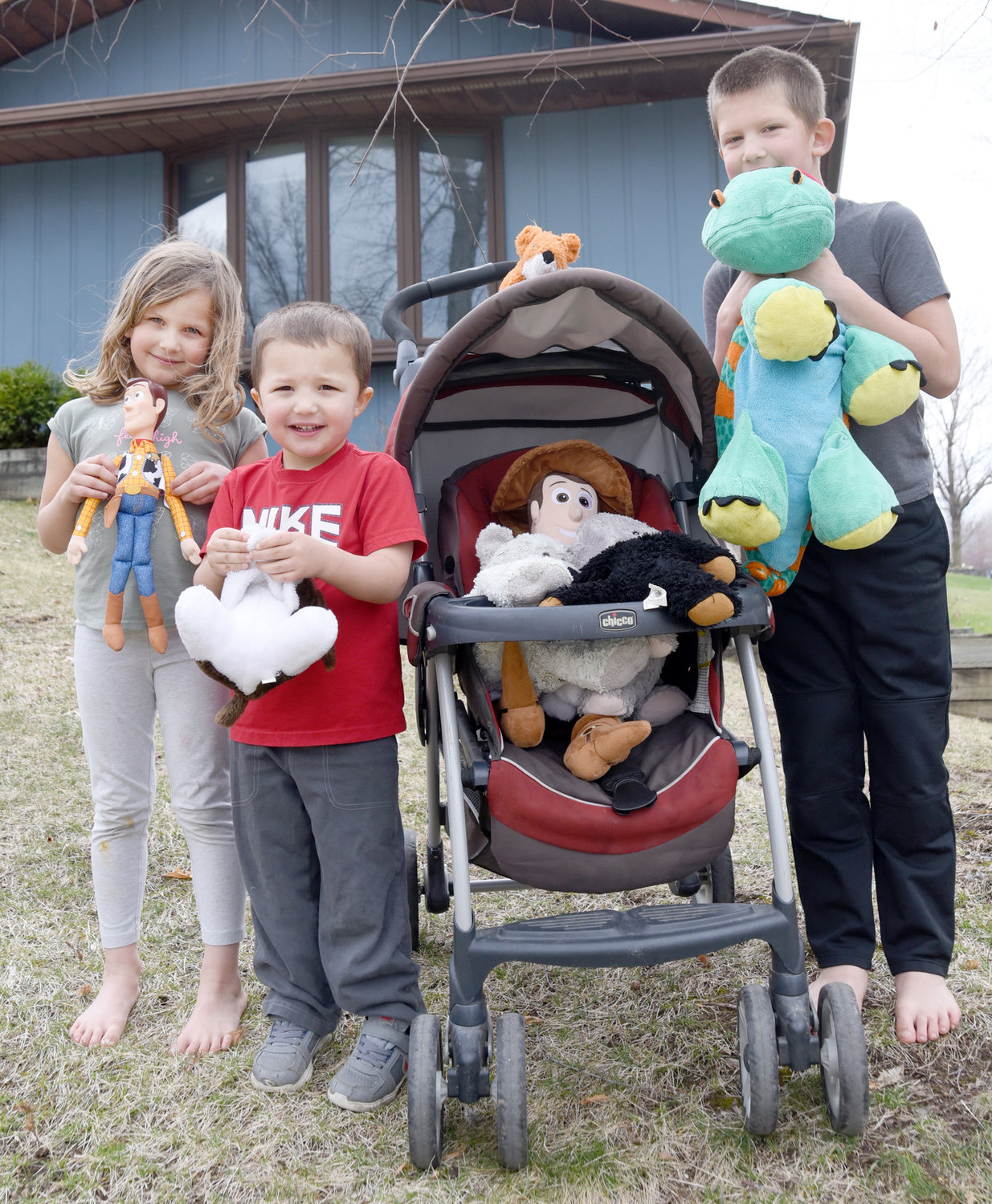 Mona, Reuben and Oliver Landes show off the bears that are decorating their front yard on K Avenue in Kalona. Mom Amy said they took a drive around the city and spotted more than 100 bears in windows.