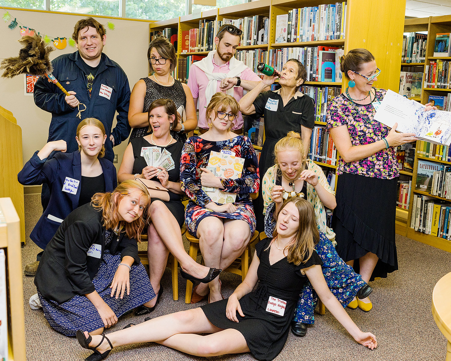 The Cast & Characters from left to right: (top row): Adam Willmore (janitor), Megan Harris (library founder), Shane Ryan (author), Lucinda Duncan (library volunteer), and Carrie Geno (children’s librarian), (middle row): Gabrielle Geno (benefactor), Lisa Lundstrom (library director), Erin Campbell (library asst. director), and Jillian Clark (adult librarian), (bottom row): Wren Harris (clerk), and Laurelin Geno (trustee).