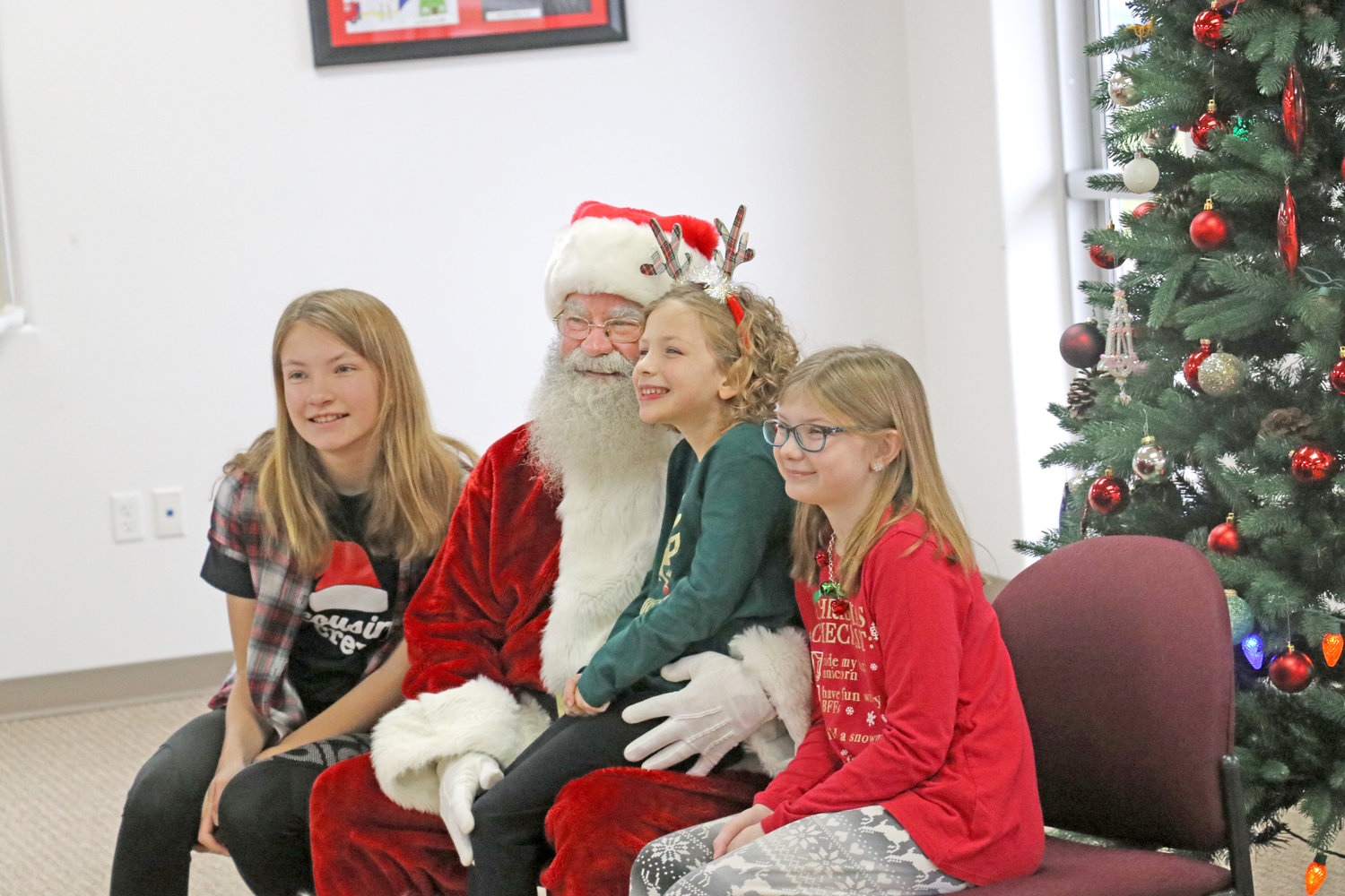 A trio of young ladies dressed festively for their photo with Mr. Claus.