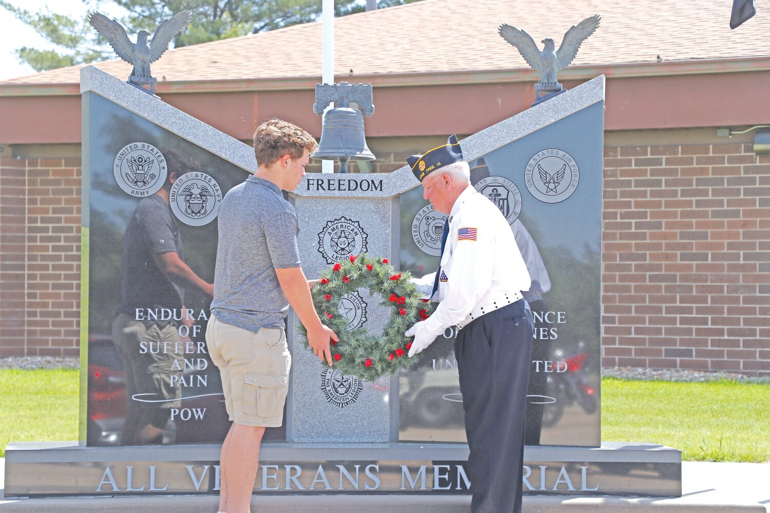 A Lone Tree resident assists the Lone Tree American Legion Color Guard in laying the wreath before the ceremonial shots on Memorial Day