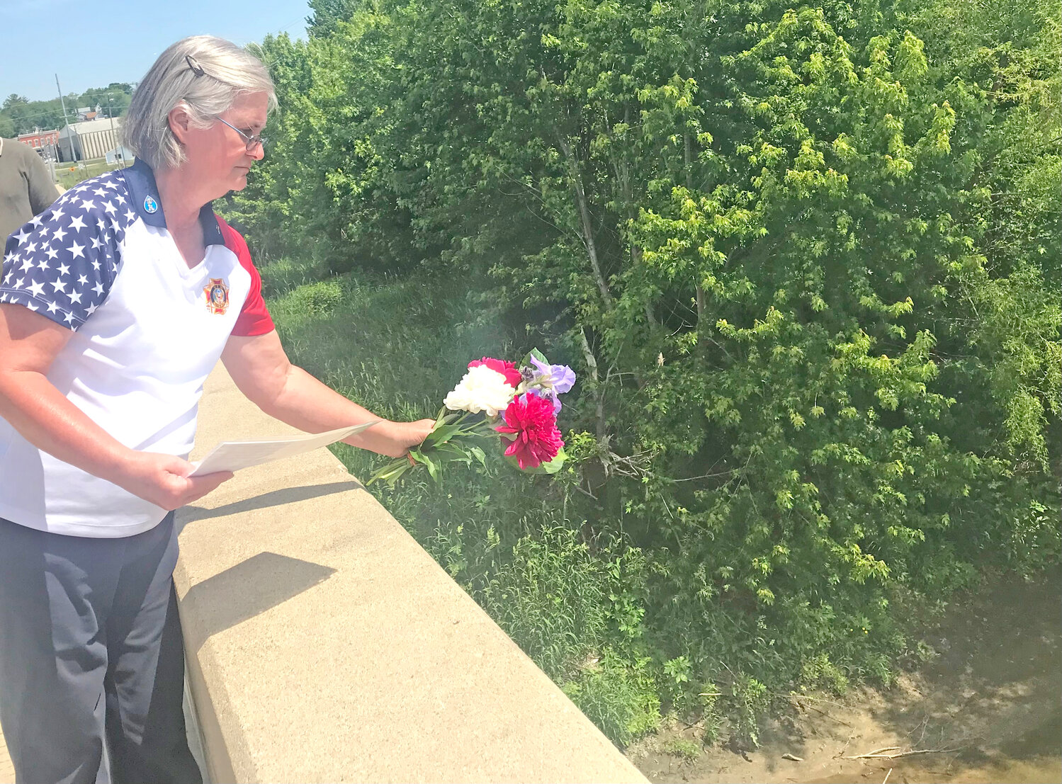Kathy Colbert, who gave the prayer at the Riverside Memorial Day service, throws flowers from the bridge to honor those lost at sea.