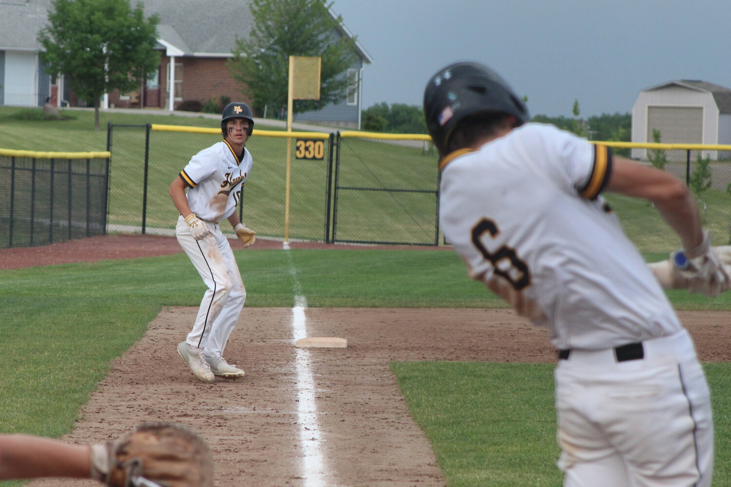Collin Miller of Mid-Prairie dances off third base as teammate Cain Brown swings into a pitch against West Branch on June 2.