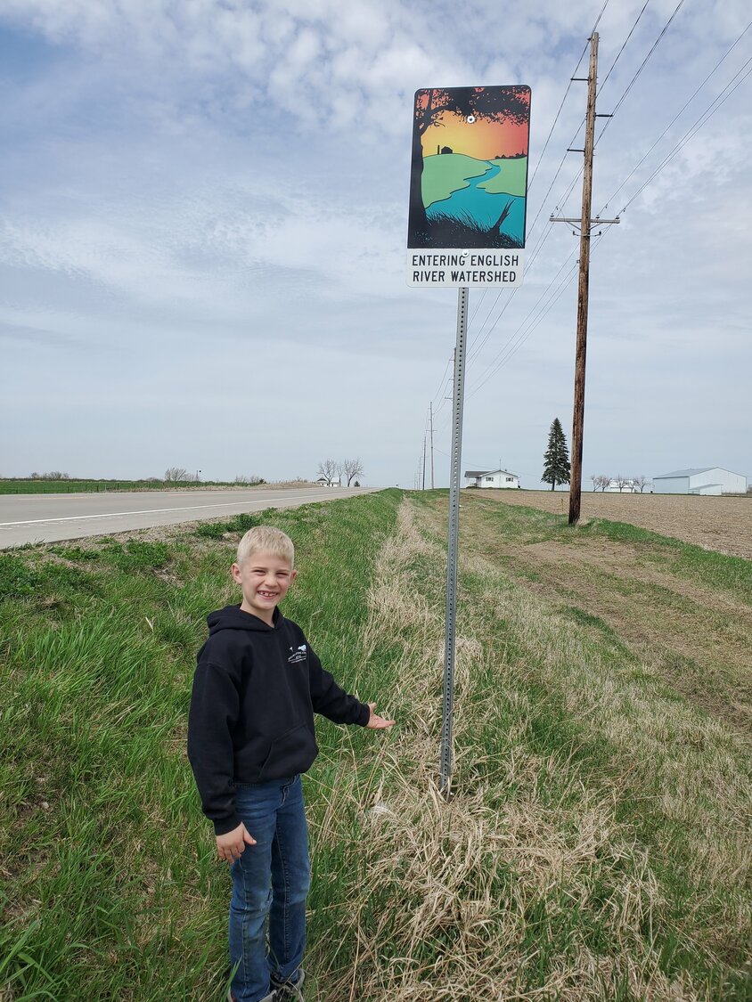 Nolan Giannini, son of soil commissioner Kate Giannini, stands next to the new Entering English River Watershed sign on Riverside Road, south of Riverside