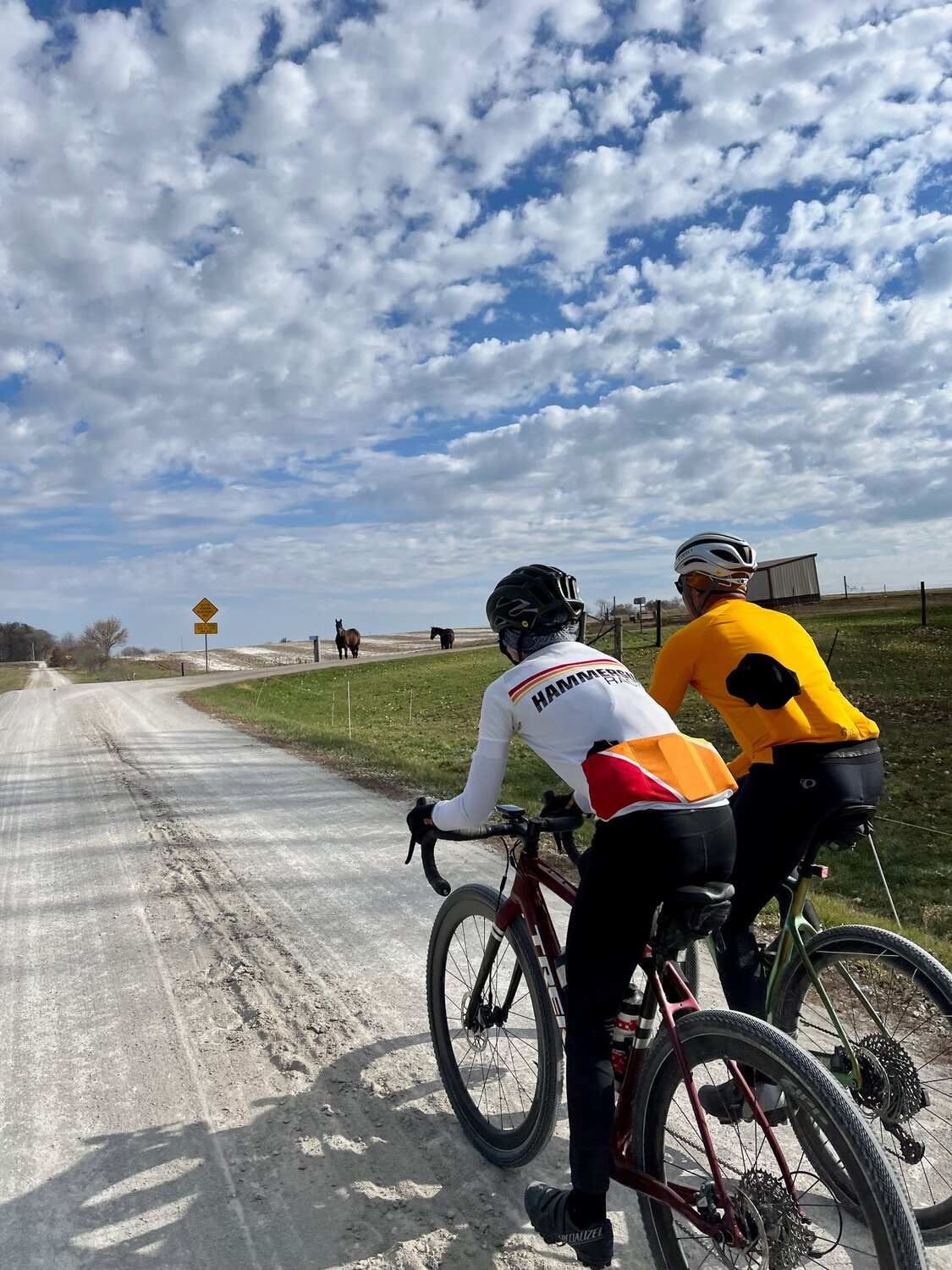 Refined gravel and horseshoe prints are characteristic of Kalona’s backroads, making them the perfect location for an Iowa Gravel Series cycling race.  Here, Mason Wilson rides with Charlie Bui north of Kalona.